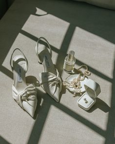 a pair of white shoes sitting on top of a floor next to a bottle of perfume