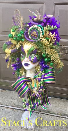 a mardi gras mask with purple, green and gold decorations on the head