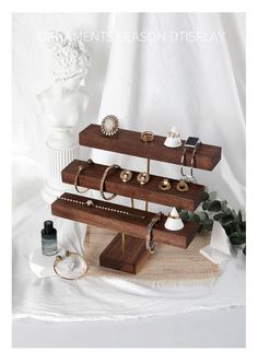 three tiered wooden jewelry rack with rings and bracelets on it, surrounded by other accessories