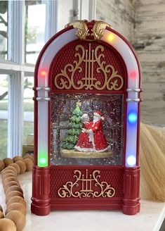 a red and white clock with a santa clause on it's face in front of a christmas tree