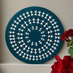 a blue and white plate sitting on top of a counter next to red flower vases