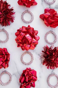 many red bows and bracelets on a white marble surface with some diamonds around them