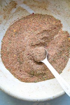 a white bowl filled with spices and a spoon