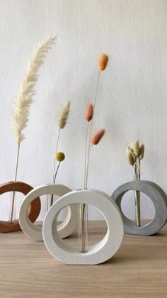 three vases sitting on top of a wooden table next to each other with dried flowers in them