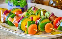 a white plate topped with veggies and meat skewers