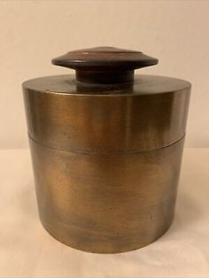 an antique brass container with a wooden lid