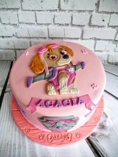 a pink birthday cake with a dog on it's top and name written across the bottom