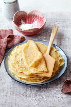 a stack of tortillas on a plate with a wooden spoon next to it