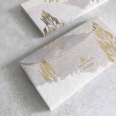 two white boxes with gold foil designs on the side and one has a knife in it