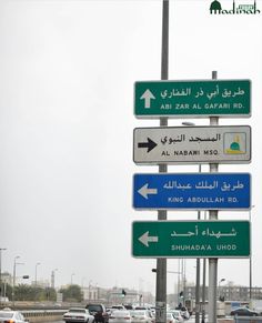 several street signs on a pole in front of a highway filled with lots of traffic