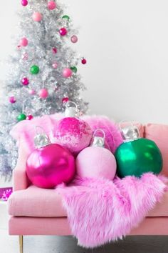 pink and green ornaments are sitting on a pink chair in front of a christmas tree