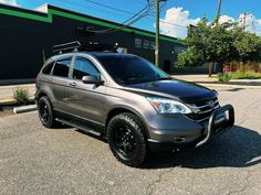 a silver suv parked in front of a building with black rims on it's tires