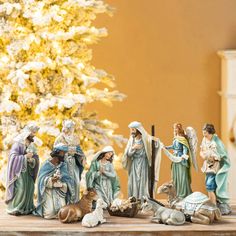 a group of figurines sitting on top of a table next to a christmas tree