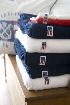 towels stacked on top of each other in front of a bed with an american flag pillow