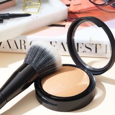 a makeup brush sitting on top of a table next to a book and eyeglasses