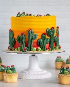 a cake with cactus decorations and cupcakes around it