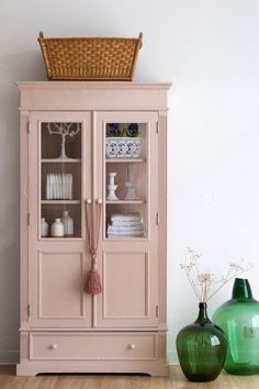 a pink china cabinet sitting next to a green vase