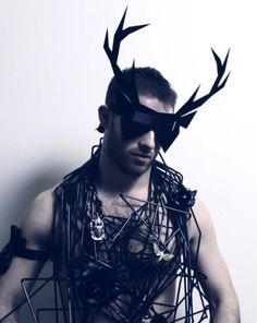 a man with antlers on his head is posing for the camera in front of a white wall