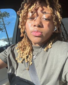 a woman with dreadlocks sitting in the back seat of a car