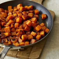 a pan filled with cooked sweet potatoes on top of a cutting board