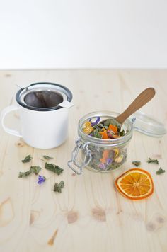 there is a cup of tea next to an orange slice and a spoon on the table