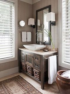 a bathroom with a sink, mirror and rug in front of the window that has shutters