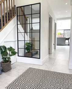 a large mirror sitting on the side of a white wall next to a stair case