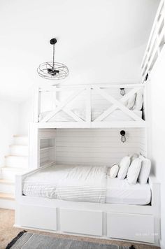 a white bunk bed with drawers underneath it and a chandelier hanging from the ceiling