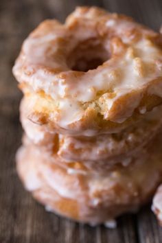 a stack of glazed donuts sitting on top of a wooden table next to each other