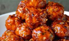 a white bowl filled with meatballs covered in bbq sauce on top of a wooden table