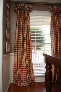 the curtains are hanging in front of the window with wooden flooring and brown walls