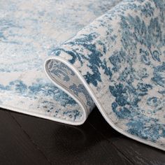 a blue and white rug on the floor with a black wood flooring underneath it