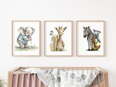 three pictures of animals hanging on the wall above a crib with a baby's blanket