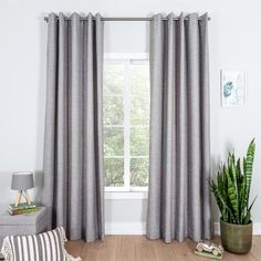 a living room filled with furniture and a large window covered in grey drapes next to a potted plant