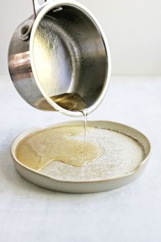 a person pouring something into a bowl on top of a plate