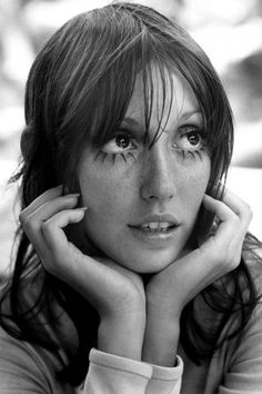 a black and white photo of a woman with freckles on her face looking at the camera