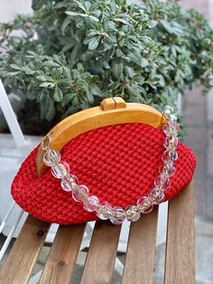 a red purse sitting on top of a wooden bench