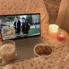 an open laptop computer sitting on top of a table next to cookies and candles in front of it