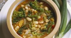 a bowl filled with beans and greens on top of a white plate