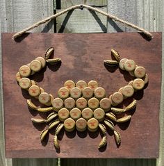 a crab made out of wine corks is hanging on a wooden board with rope