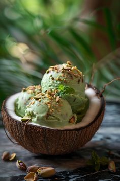 two scoops of ice cream sit in a coconut shell on a table with leaves