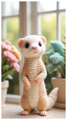 a crocheted rat standing on its hind legs in front of a potted plant