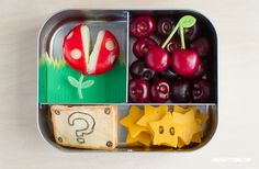 a metal container filled with fruit and veggies on top of a white table