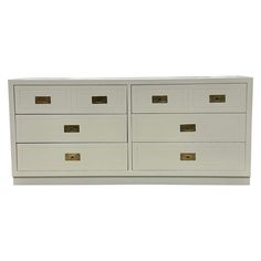 a white dresser with gold handles and drawers on the bottom drawer, against a white background