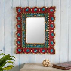 a mirror hanging on the wall next to a table with a book and potted plant