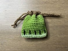 a crocheted green bag sitting on top of a wooden table next to a string