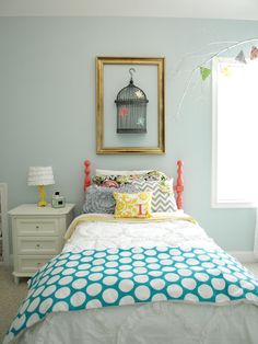 a bedroom with blue walls, white bedding and a birdcage on the wall