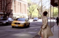 a woman is standing on the sidewalk waving