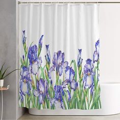 a shower curtain with blue flowers on it in a white bathroom next to a bathtub