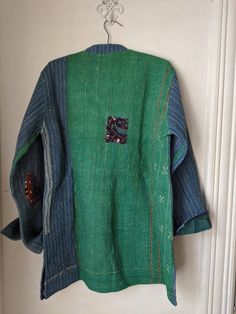 a green jacket hanging on a white door with a blue and red patchwork design